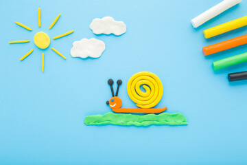 Created snail, sun and clouds from colorful modeling clay on light blue table background. Pastel color. Closeup. Little child handcraft. Top down view. © fotoduets