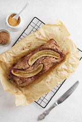 Homemade banana bread topping close-up on board on table. Vertical top view from above