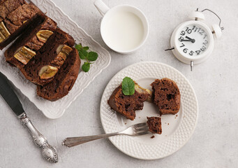 healthy evening snack with milk and banana bread and pieces on the plate and alarm, top view