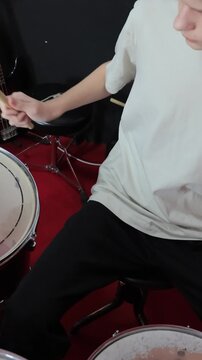 Boy playing drums with drumsticks
