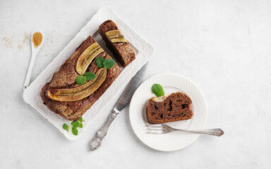 Homemade banana bread with chocolate on the plate and piece on the plate nearby close-up on table. Horizontal top view, copy space