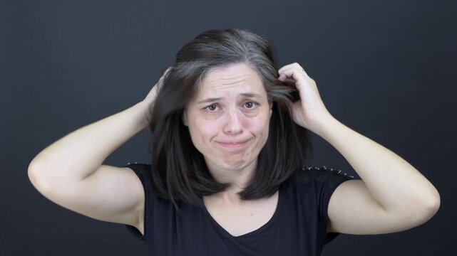 Unhappy middle-aged woman showing her graying hair