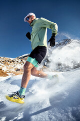 Man running at snow trail in the winter mountains