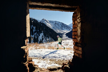 Man running at the trail in the winter mountains