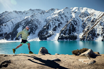 Man running at the trail in the winter mountains