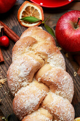 Festive bread on the table. Red christmas decorations in the background.