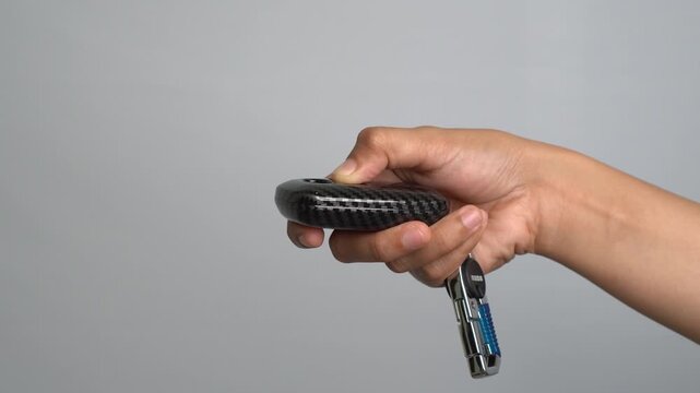 Hand Holding Modern Car Key Fob with Keyring Against Gray Background