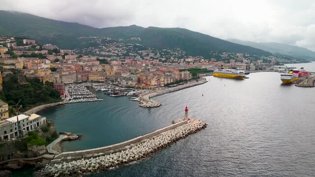 Cinematic Aerial Approach Shot Over Bastia's Mediterranean Waterfront, Highlighting the Colorful Historic Old Port and Fortified Genoese Citadel, Corsica, France.