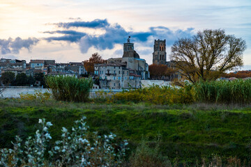 Obraz premium City of Pont-Saint-Esprit with its churches Saint-Saturnin and Saint-Pierre seen from the left bank of the Rhône at sunset