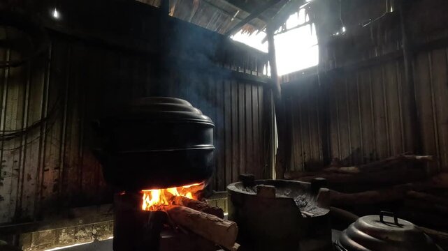Traditional Vietnamese cooking scene with a large black pot placed over a wood-fired stove inside a rustic kitchen.	
