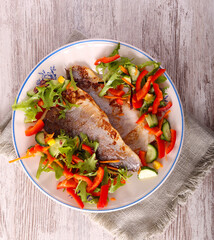 Fried fish fillet with salad on plate