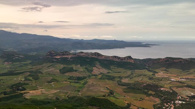 High Altitude Aerial Drone Tracking Shot Over Lush Green Inland Corsican Hills Flying North Towards Bastia City Under an Overcast Spring Sky.