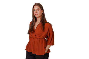 Confident young adult woman posing in orange blouse with hands in pockets on transparent background