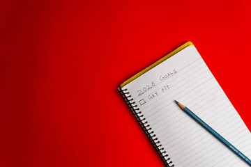 2026 goals list with push pins, an indoor plant and a sticky note on red background. Creative New...