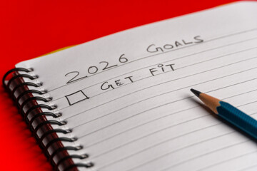 2026 goals list with push pins, an indoor plant and a sticky note on red background. Creative New...