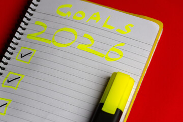2026 goals list with push pins, an indoor plant and a sticky note on red background. Creative New...