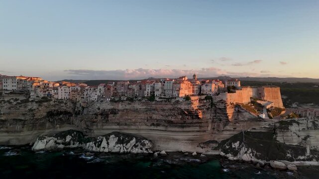 Expansive Aerial Drone Pan Across the Dramatic White Limestone Cliffs of Bonifacio, Revealing the Historic Citadel City and Turquoise Mediterranean Coastline at Sunrise, Corsica, France.