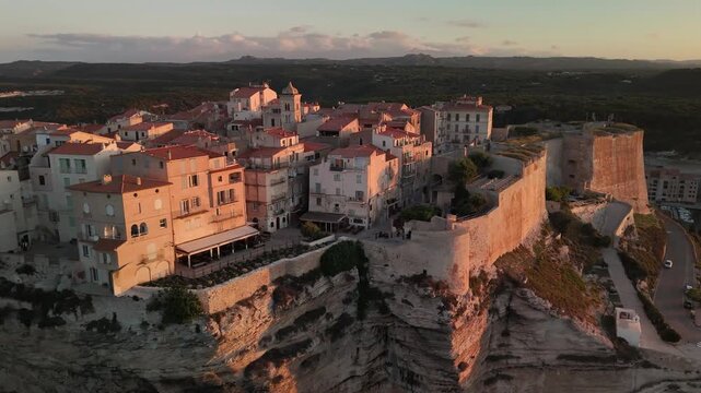 Smooth Aerial Drone Pan Across the Historic Bonifacio Citadel City, Revealing Dramatic White Limestone Cliffs and the Mediterranean Coastline at Golden Hour in Corsica, France.