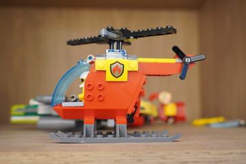 Naklejka premium A detailed shot of a Lego City fire helicopter toy on a wooden surface.