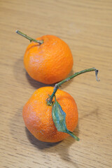 Fresh tangerines with stems and leaves on a wooden table, close-up shot