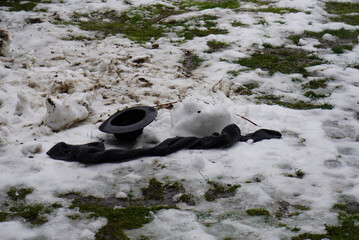 Snowy scene with a hat and scarf on the ground, winter landscape