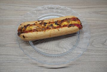 Delicious baked sandwich with cheese and vegetables on a clear plate