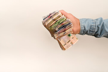hand holds a substantial stack of paper money, Ukrainian hryvnia. concepts of wealth, economic growth and financial opportunity on white background. male hand displays a thick bundle of cash,