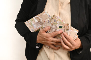 woman in business clothing holds large stacks of banknotes close to chest. personal wealth and financial success. Hands firmly embrace money bundles, symbolizing savings, investment.