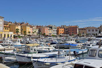 Rovinj town harbor with numerous boats and old buildings. Boats moored in a busy harbor with colorful buildings of Rovinj Old Town under a clear blue sky.