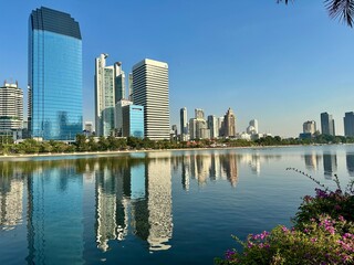 Fototapeta premium Benchakitti Park Bangkok skyline with modern skyscrapers reflected in lake – urban cityscape Thailand