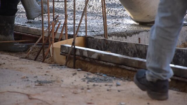Construction workers pour concrete floors, Concrete pouring during commercial floor construction faceless workers coordinating defocused, Construction workers pouring concrete over metal grid with cem
