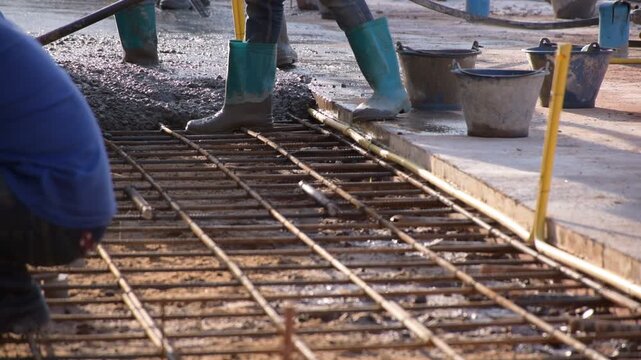 Construction workers pour concrete floors, Concrete pouring during commercial floor construction faceless workers coordinating defocused, Construction workers pouring concrete over metal grid with cem