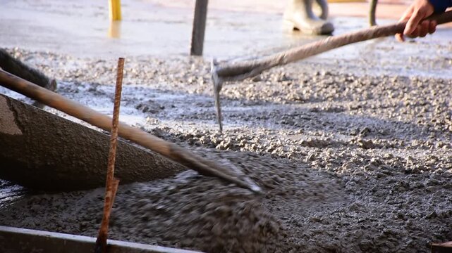 Construction workers pour concrete floors, Concrete pouring during commercial floor construction faceless workers coordinating defocused, Construction workers pouring concrete over metal grid with cem