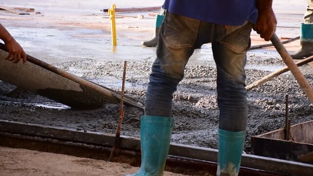 Construction workers pour concrete floors, Concrete pouring during commercial floor construction faceless workers coordinating defocused, Construction workers pouring concrete over metal grid with cem