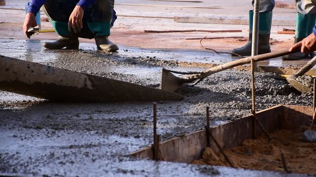 Construction workers pour concrete floors, Concrete pouring during commercial floor construction faceless workers coordinating defocused, Construction workers pouring concrete over metal grid with cem