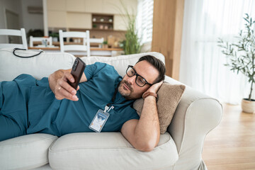 Healthcare worker relaxing on sofa using mobile phone