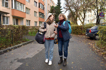 Obraz premium Mother and teenager daughter walking arm in arm on an urban street