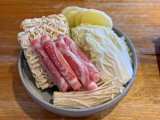 Ready-to-Cook Hot Pot Platter Featuring Raw Beef Slices, Instant Noodles, Napa Cabbage, Enoki Mushrooms, and Potato Slices