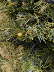 Vibrant Artificial Christmas Tree Foliage Illuminated by a Single Warm Yellow Fairy Light for Festive Decor