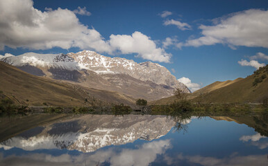 Snow-capped Caucasus Mountains and lake on a sunny summer day