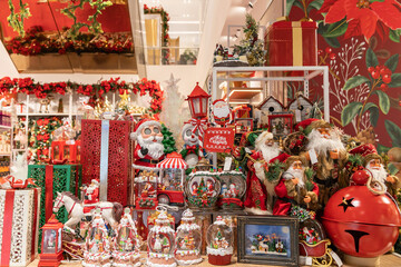 Naklejka premium A colorful Christmas window display showcases Santa figurines, wrapped gifts, ornate ornaments, and lively holiday decor