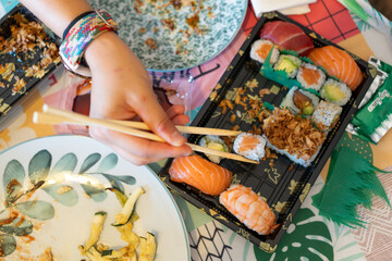Person eating sushi with chopsticks from takeaway box © Jorge