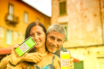Happy couple visiting city with covid green pass. Man and woman ready to go on a trip with screenshots of the vaccination.