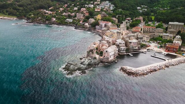 Cinematic Aerial Drone Descent into Erbalunga Fishing Village, Highlighting the Ruined Genoese Tower, Colorful Houses, and Boats in the Historic Port on the Eastern Coast of Cap Corse, Corsica,...