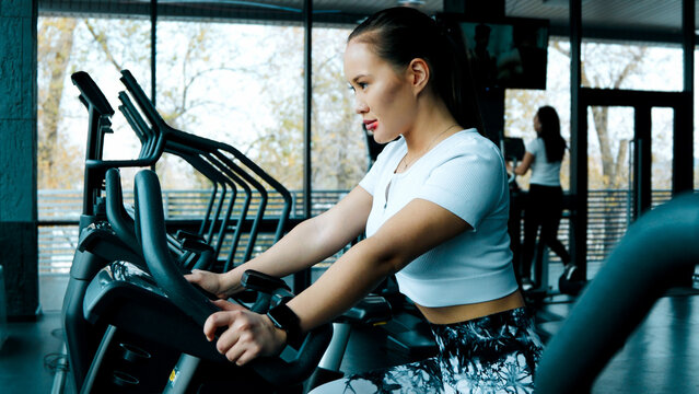 A woman is using a seated rowing machine to work her back muscles - Powered by Adobe