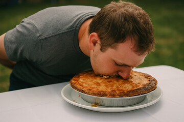 Gastronomic Devotion: A dedicated individual immerses himself fully in the experience of a large pie, displaying unwavering commitment to the culinary delight.