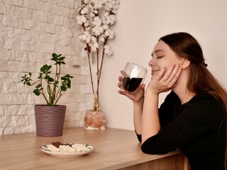 Woman enjoying a morning cup of coffee while preparing breakfast or a meal in her cozy kitchen at home. Concept of domestic comfort, relaxation, and healthy routine.