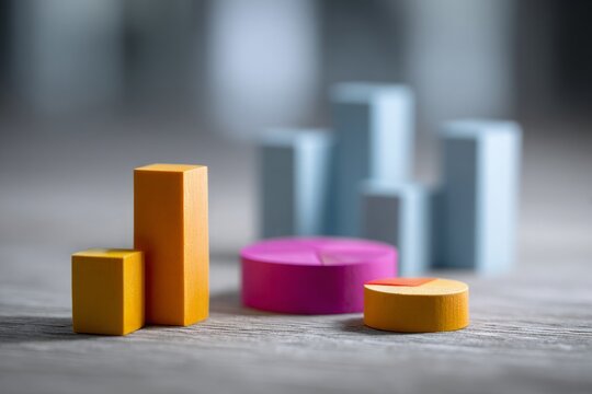 Wooden blocks form financial bar charts and pie charts, representing business data on grey background.