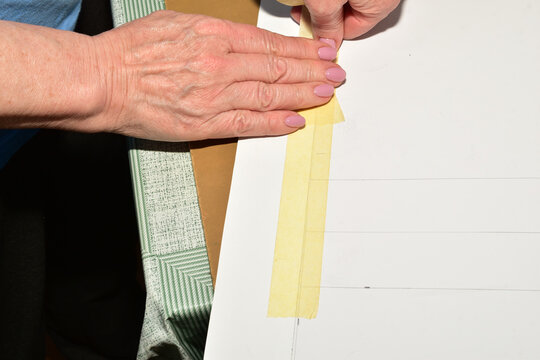 The cutter makes a pattern for the fabric by gluing the parts of the pattern together with tape.