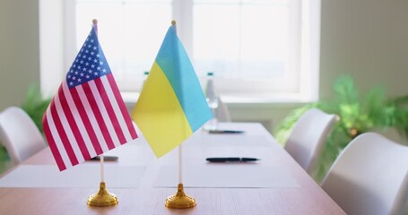 Close-up two flags placed on meeting table, representing United States or USA and Ukraine countries, as symbols of politics negotiation. International relations, diplomacy, global affairs concept - Powered by Adobe